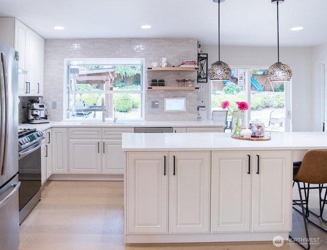 903 198th Ave E, Lake Tapps, WA 98391 - kitchen with appliances with stainless steel finishes, decorative backsplash, white cabinetry, light wood-type flooring, and light countertops