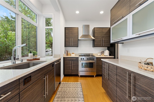 201 20th Ave E, Seattle, WA 98112 - kitchen with wall chimney exhaust hood, stainless steel appliances, dark brown cabinetry, light wood-style floors, and recessed lighting