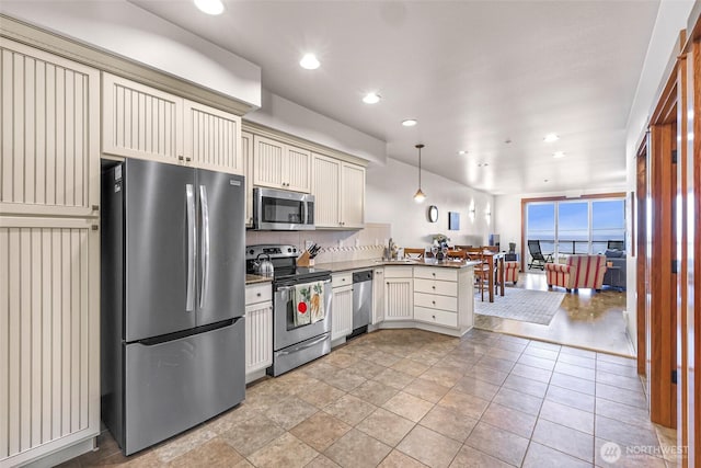 7714 Birch Bay Dr Unit 203, Blaine, WA 98230 - kitchen featuring appliances with stainless steel finishes, cream cabinetry, a peninsula, dark countertops, and decorative backsplash