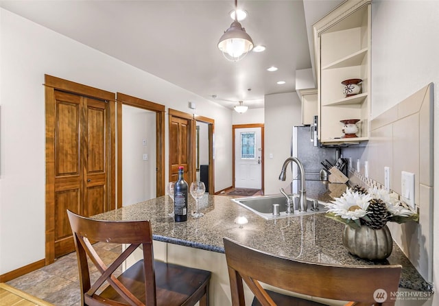 7714 Birch Bay Dr Unit 203, Blaine, WA 98230 - kitchen with a peninsula, open shelves, a kitchen bar, freestanding refrigerator, and dark stone countertops