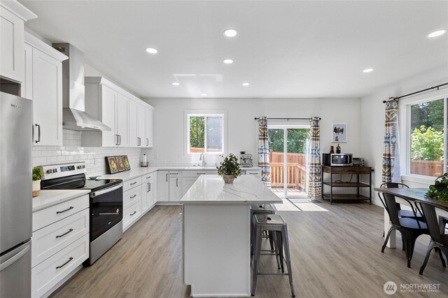 7952 Apache Dr, Maple Falls, WA 98266 - kitchen with stainless steel appliances, wall chimney exhaust hood, plenty of natural light, a kitchen island, and recessed lighting