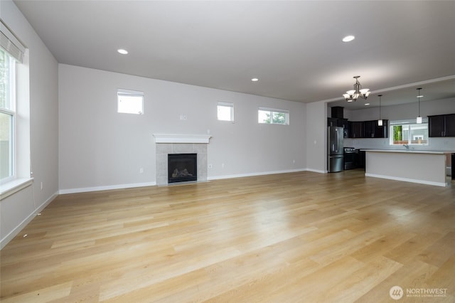 128 N Trail Rd, Sedro Woolley, WA 98284 - unfurnished living room with a chandelier, a tile fireplace, plenty of natural light, light wood-type flooring, and recessed lighting