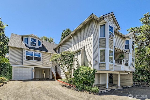 17201 127th Pl NE Unit 101, Woodinville, WA 98072 - view of front of property with an attached garage, stairs, driveway, a shingled roof, and a balcony