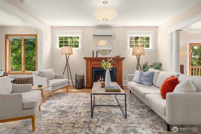 2401 10th Ave W, Seattle, WA 98119 - living area featuring an AC wall unit, radiator heating unit, a warm lit fireplace, ornate columns, and wood finished floors
