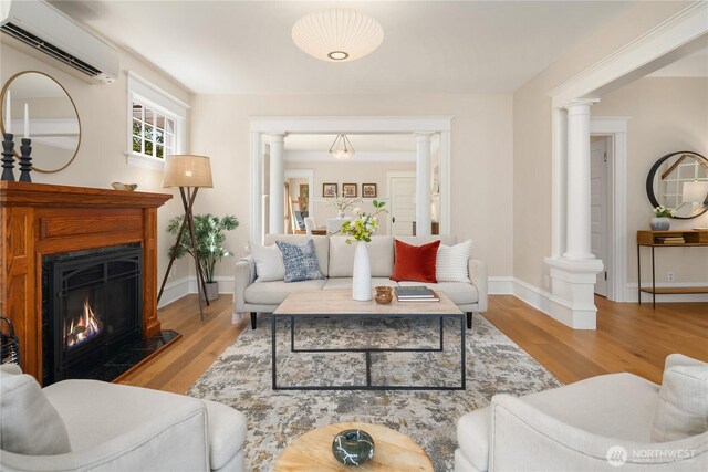 2401 10th Ave W, Seattle, WA 98119 - living area featuring a wall mounted AC, ornate columns, wood finished floors, and a lit fireplace