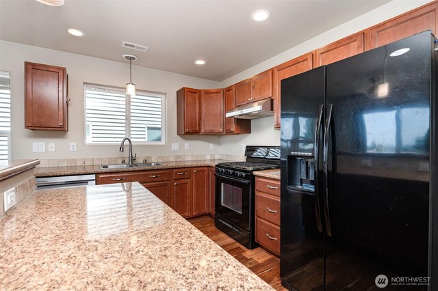 1228 81st Dr SE, Lake Stevens, WA 98258 - kitchen with black appliances, under cabinet range hood, dark wood finished floors, brown cabinets, and decorative light fixtures