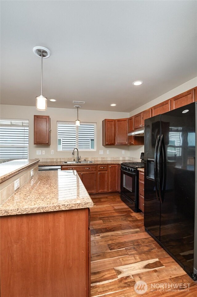 1228 81st Dr SE, Lake Stevens, WA 98258 - kitchen with black appliances, under cabinet range hood, brown cabinets, light wood-style floors, and pendant lighting