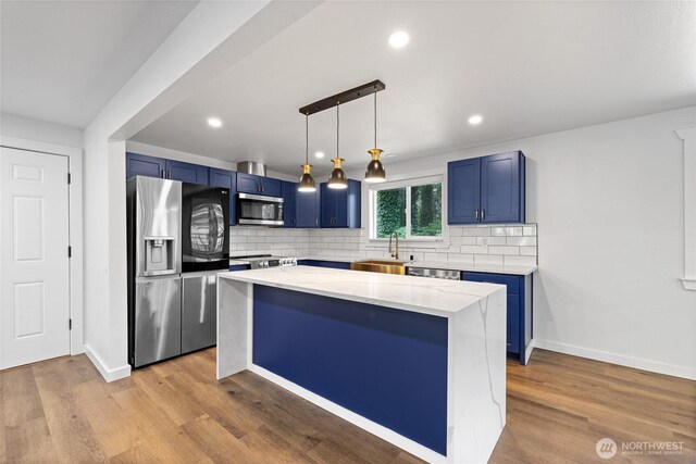 5206 68th Ave W, University Place, WA 98467 - kitchen with appliances with stainless steel finishes, blue cabinets, tasteful backsplash, light stone counters, and recessed lighting