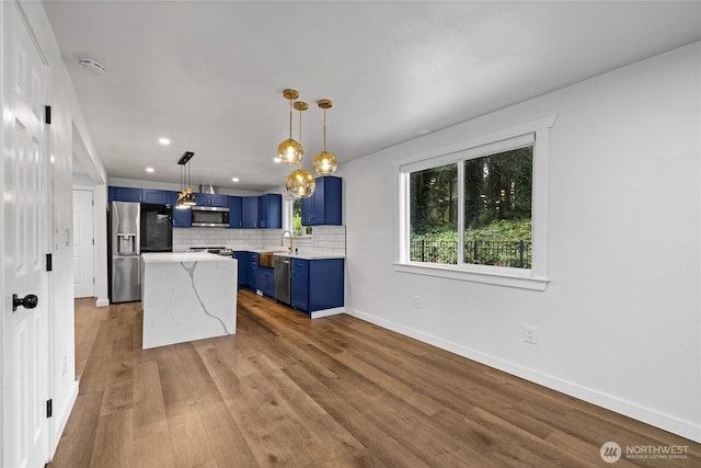 5206 68th Ave W, University Place, WA 98467 - kitchen with blue cabinets, appliances with stainless steel finishes, dark wood finished floors, backsplash, and a kitchen island