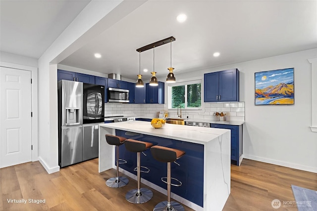 5206 68th Ave W, University Place, WA 98467 - kitchen with stainless steel appliances, blue cabinetry, a breakfast bar area, tasteful backsplash, and a kitchen island