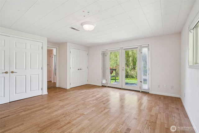 11112 E Riverside Dr, Bothell, WA 98011 - unfurnished bedroom featuring access to exterior, light wood-style flooring, and multiple closets