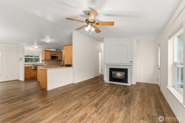 158 S Fork Rd, Raymond, WA 98577 - unfurnished living room with wood finished floors, a fireplace with flush hearth, plenty of natural light, a ceiling fan, and vaulted ceiling