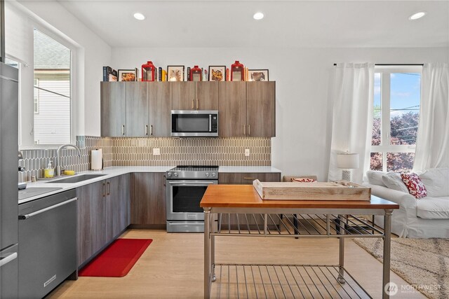 1734 NW 62nd St Unit A, Seattle, WA 98107 - kitchen featuring stainless steel appliances, light countertops, light wood finished floors, plenty of natural light, and recessed lighting