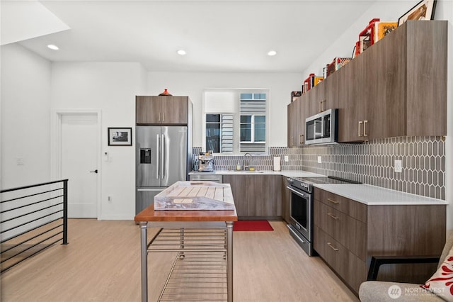 1734 NW 62nd St Unit A, Seattle, WA 98107 - kitchen with appliances with stainless steel finishes, modern cabinets, light wood-style flooring, light countertops, and recessed lighting