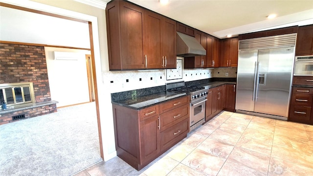 3410 Forest Ct, Bellingham, WA 98225 - kitchen featuring high quality appliances, range hood, backsplash, dark stone countertops, and a brick fireplace