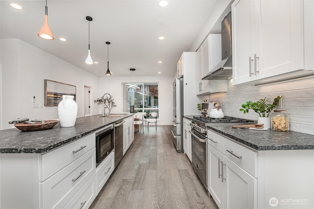 7731 NE 175th St Unit 102, Kenmore, WA 98028 - kitchen with premium appliances, wall chimney exhaust hood, light wood-style flooring, white cabinets, and recessed lighting