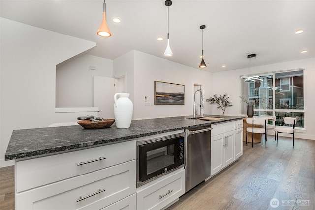 7731 NE 175th St Unit 102, Kenmore, WA 98028 - kitchen with black microwave, dishwasher, light wood-style flooring, white cabinetry, and dark stone counters