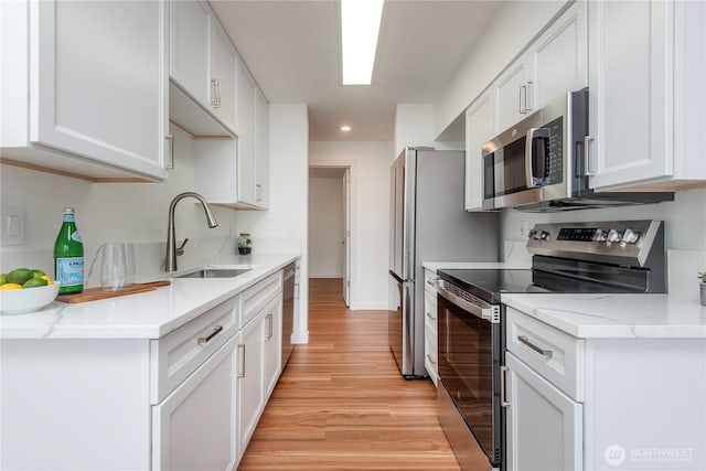 1000 NE 88th St Unit 303, Seattle, WA 98115 - kitchen featuring appliances with stainless steel finishes, light wood finished floors, recessed lighting, white cabinets, and light stone countertops