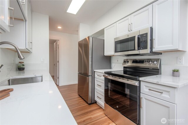 1000 NE 88th St Unit 303, Seattle, WA 98115 - kitchen featuring stainless steel appliances, white cabinetry, light wood finished floors, recessed lighting, and light stone counters