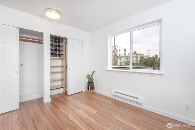 1000 NE 88th St Unit 303, Seattle, WA 98115 - unfurnished bedroom with baseboard heating, multiple closets, and light wood-style flooring