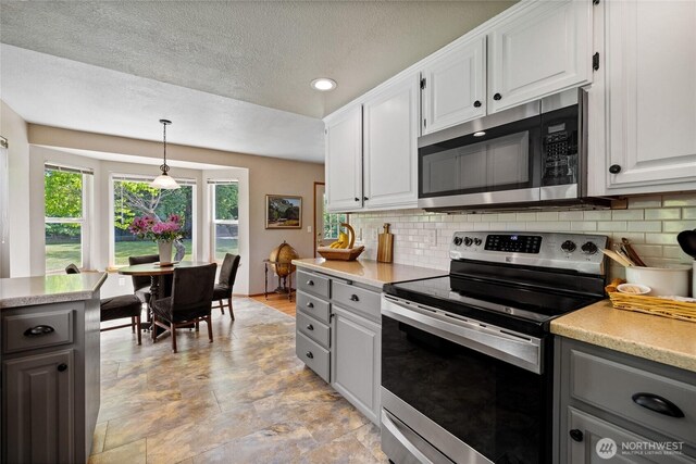 16325 Tareyton Ln SE, Yelm, WA 98597 - kitchen with stainless steel appliances, gray cabinets, tasteful backsplash, light countertops, and white cabinetry