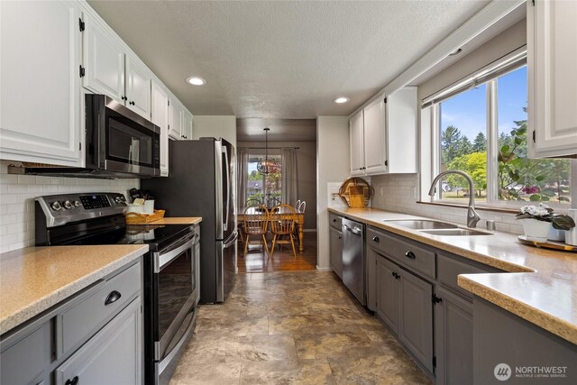 16325 Tareyton Ln SE, Yelm, WA 98597 - kitchen featuring appliances with stainless steel finishes, a textured ceiling, gray cabinetry, white cabinets, and light countertops