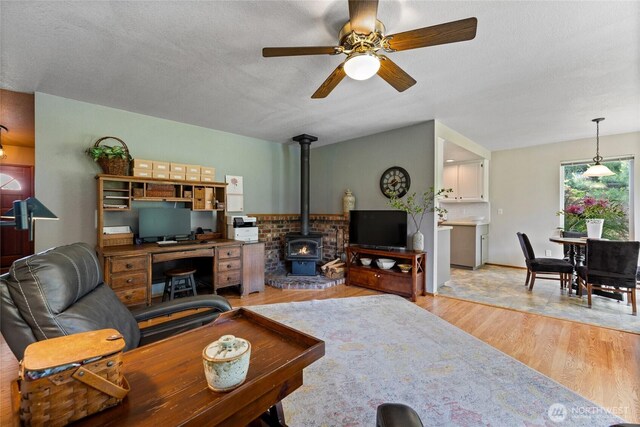 16325 Tareyton Ln SE, Yelm, WA 98597 - living area featuring a wood stove, light wood-style flooring, ceiling fan, and a textured ceiling