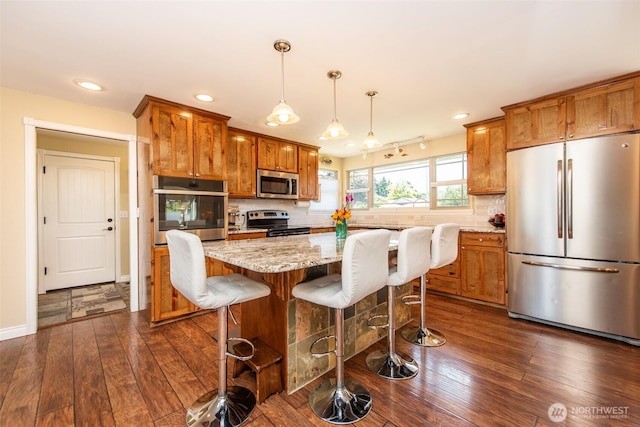 516 E Willow St, Sequim, WA 98382 - kitchen featuring stainless steel appliances, brown cabinetry, dark wood-style flooring, recessed lighting, and decorative backsplash