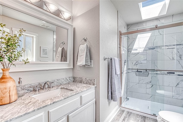 87 N Mary Ave, East Wenatchee, WA 98802 - bathroom featuring vanity, a stall shower, wood finished floors, a skylight, and a textured wall
