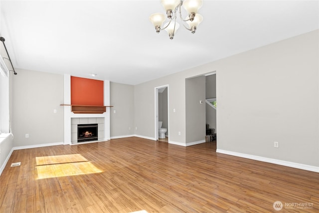26822 27th Ave S, Kent, WA 98032 - unfurnished living room with a chandelier, light wood-style flooring, and a tiled fireplace