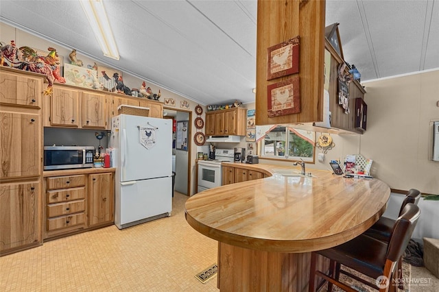45019 Cougi Dr N, Davenport, WA 99122 - kitchen with white appliances, light countertops, a peninsula, a breakfast bar, and vaulted ceiling