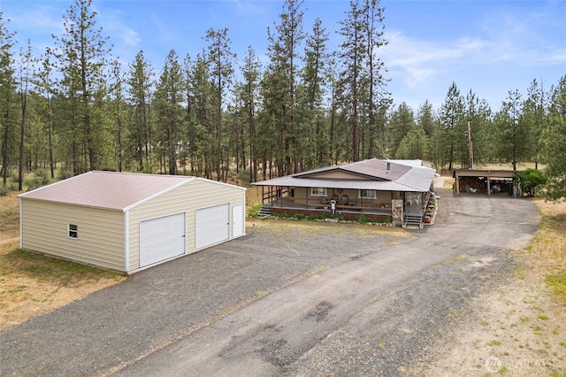 45019 Cougi Dr N, Davenport, WA 99122 - view of front facade featuring an outdoor structure, a metal roof, a garage, and a view of trees