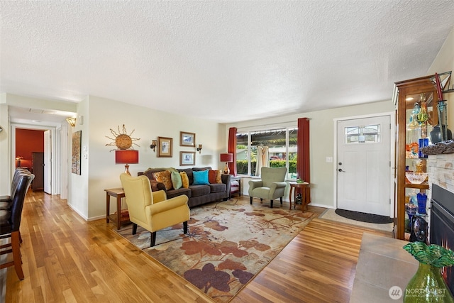 1227 137th St E, Tacoma, WA 98445 - living room with light wood finished floors, a textured ceiling, and a fireplace with flush hearth
