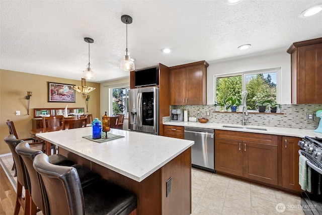 1227 137th St E, Tacoma, WA 98445 - kitchen featuring stainless steel appliances, a textured ceiling, decorative backsplash, a center island, and decorative light fixtures