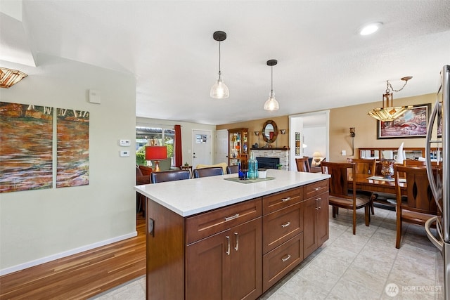 1227 137th St E, Tacoma, WA 98445 - kitchen featuring a fireplace, light countertops, decorative light fixtures, a kitchen island, and freestanding refrigerator