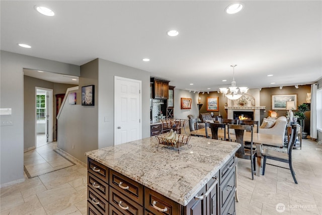 23017 138th Ave E, Graham, WA 98338 - kitchen with recessed lighting, a chandelier, decorative light fixtures, a lit fireplace, and light stone counters