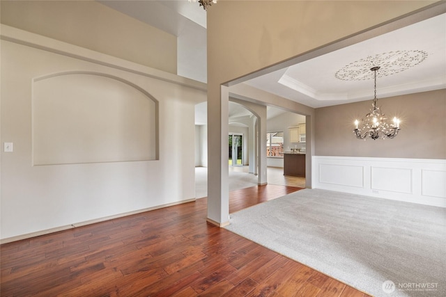 4703 235th St E, Spanaway, WA 98387 - foyer entrance featuring a chandelier, wood finished floors, arched walkways, wainscoting, and a raised ceiling