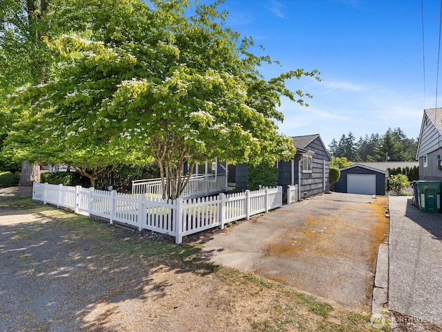 14324 Wayne Pl N, Seattle, WA 98133 - obstructed view of property featuring driveway, a garage, a fenced front yard, and an outbuilding