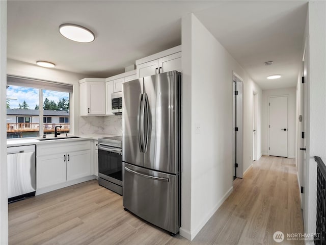 17301 6th Ave E, Spanaway, WA 98387 - kitchen with appliances with stainless steel finishes, light wood-style flooring, white cabinets, and decorative backsplash