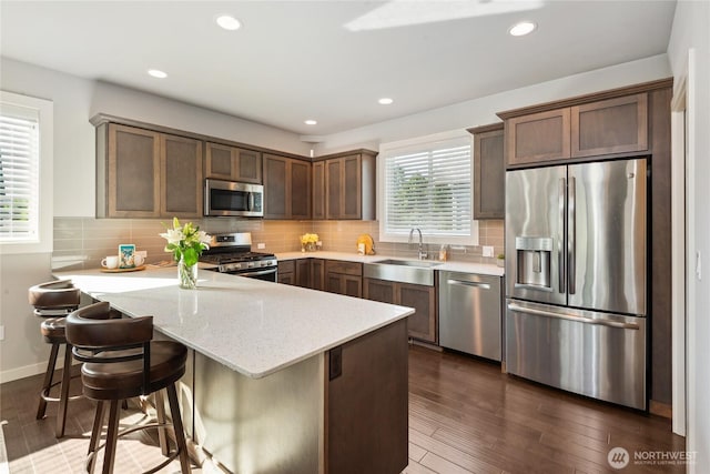 795 NE 2nd St, North Bend, WA 98045 - kitchen with appliances with stainless steel finishes, a peninsula, dark wood-type flooring, light stone countertops, and decorative backsplash