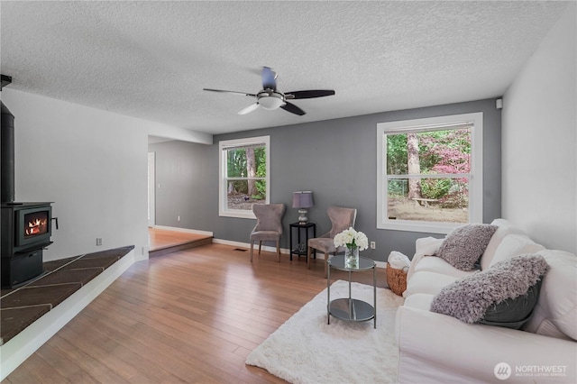 13719 Pinehurst Ln NW, Gig Harbor, WA 98329 - living area featuring wood finished floors, a wood stove, ceiling fan, plenty of natural light, and a textured ceiling