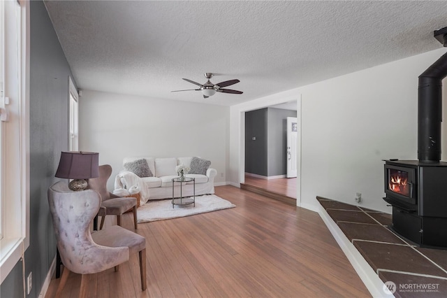 13719 Pinehurst Ln NW, Gig Harbor, WA 98329 - living room with a wood stove, a ceiling fan, a textured ceiling, and wood finished floors