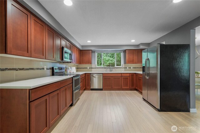 13719 Pinehurst Ln NW, Gig Harbor, WA 98329 - kitchen with stainless steel appliances, light wood-type flooring, tasteful backsplash, light countertops, and recessed lighting
