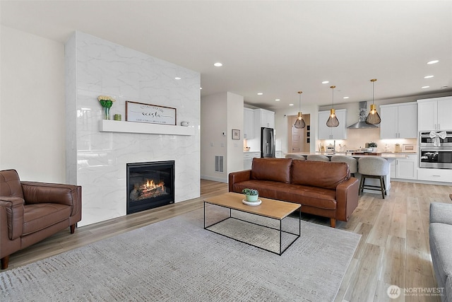 18740 130th St E, Bonney Lake, WA 98391 - living room featuring light wood-style flooring, recessed lighting, and a fireplace