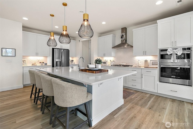 18740 130th St E, Bonney Lake, WA 98391 - kitchen featuring stainless steel appliances, wall chimney exhaust hood, tasteful backsplash, light countertops, and a kitchen breakfast bar