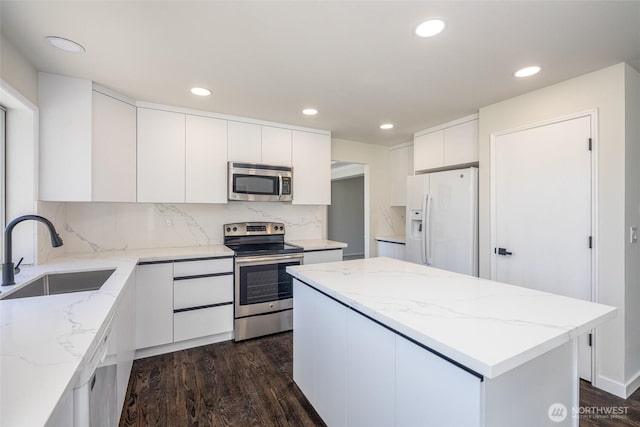 9825 S 246th Pl, Kent, WA 98030 - kitchen with appliances with stainless steel finishes, dark wood-type flooring, white cabinetry, a center island, and recessed lighting