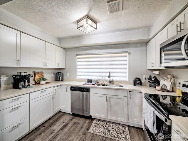 404 Nixon St S, Roy, WA 98580 - kitchen featuring appliances with stainless steel finishes, white cabinets, a textured ceiling, and dark wood-type flooring