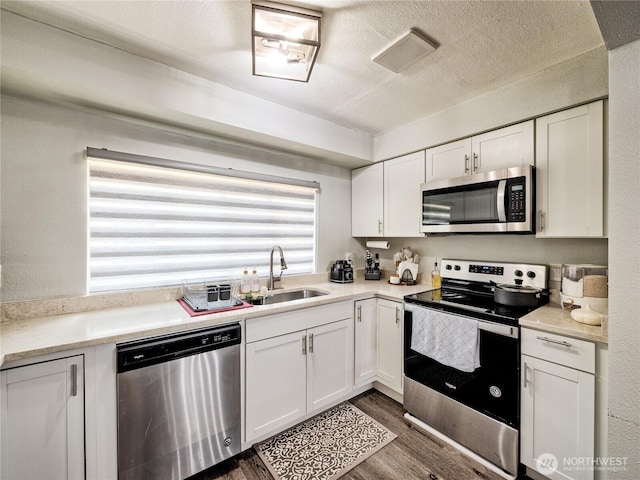 404 Nixon St S, Roy, WA 98580 - kitchen with appliances with stainless steel finishes, dark wood finished floors, white cabinetry, light countertops, and a textured ceiling