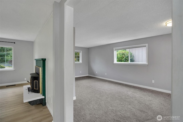 4801 78th St E, Tacoma, WA 98443 - unfurnished living room with a wood stove, a textured ceiling, healthy amount of natural light, and carpet floors