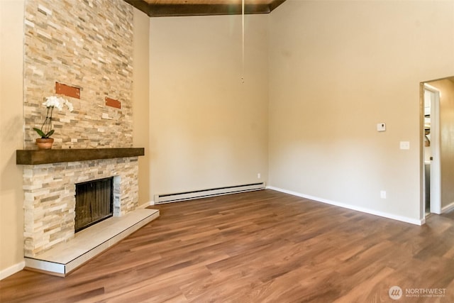 7308 N Skyview Ln Unit I-304, Tacoma, WA 98406 - unfurnished living room with a baseboard heating unit, wood finished floors, a towering ceiling, and a fireplace